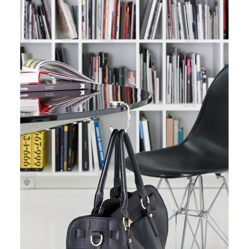 Bag hanging on a table with books nearby.