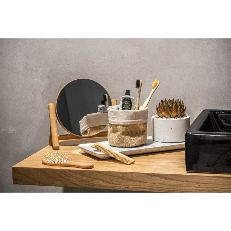 Bathroom essentials on wooden shelf, mirror and plant.