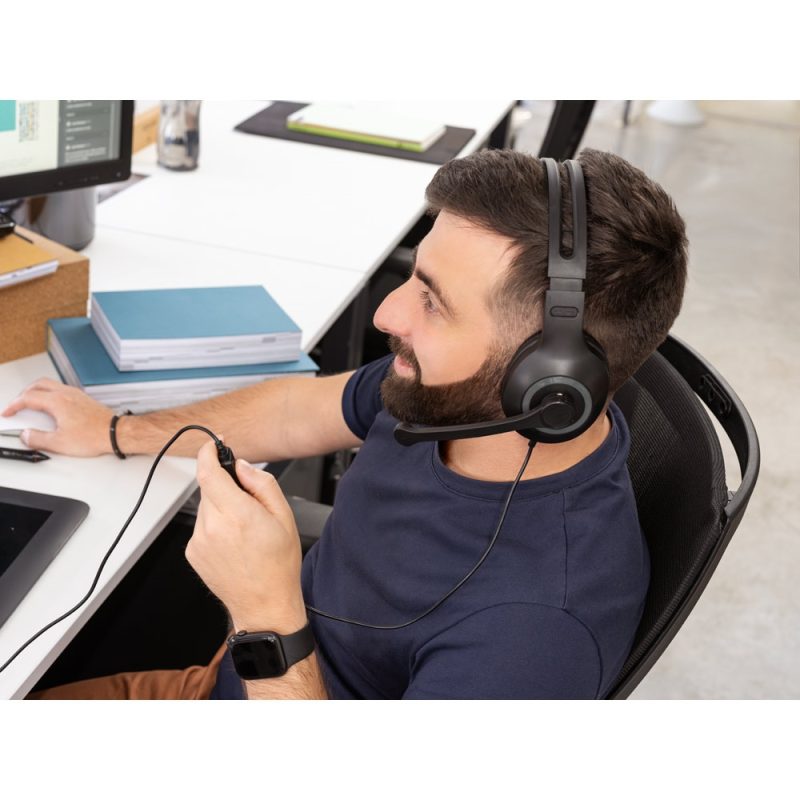 Man with headset working at computer desk.