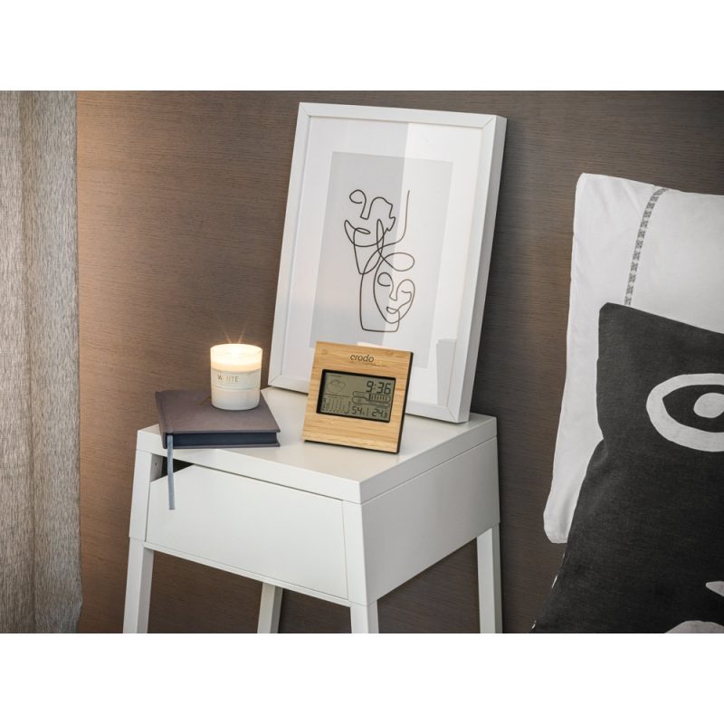 Bedside table with clock, candle, and abstract art.