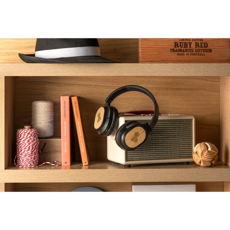 Headphones resting on vintage speaker on wooden shelf.
