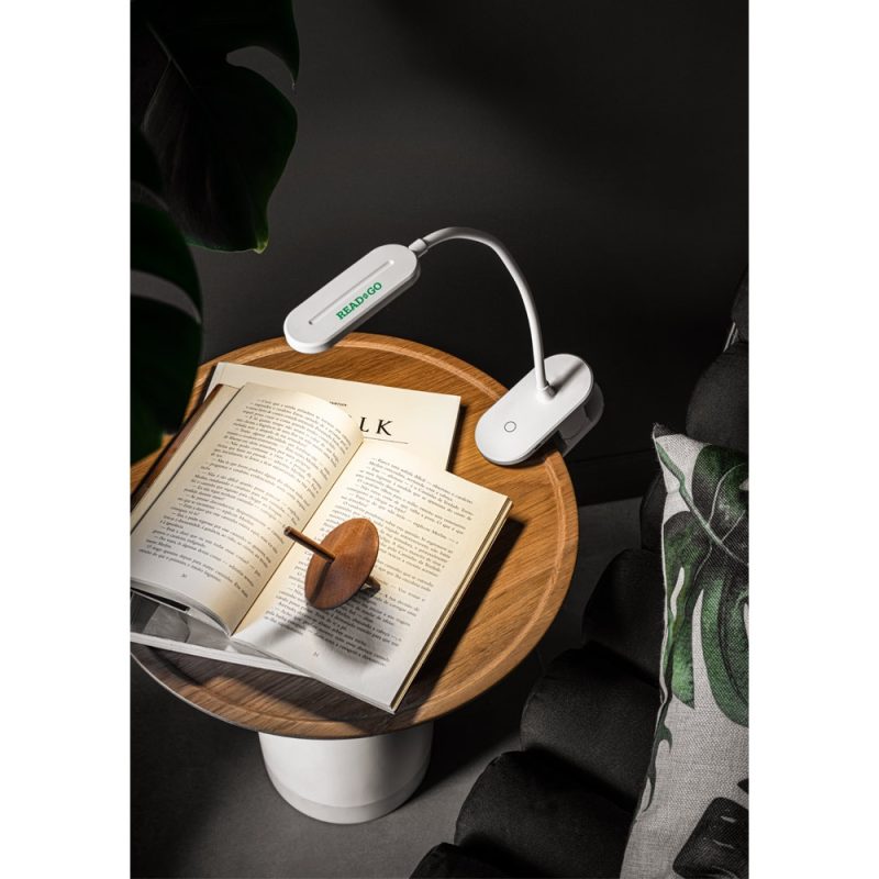 Book with reading light on wooden table