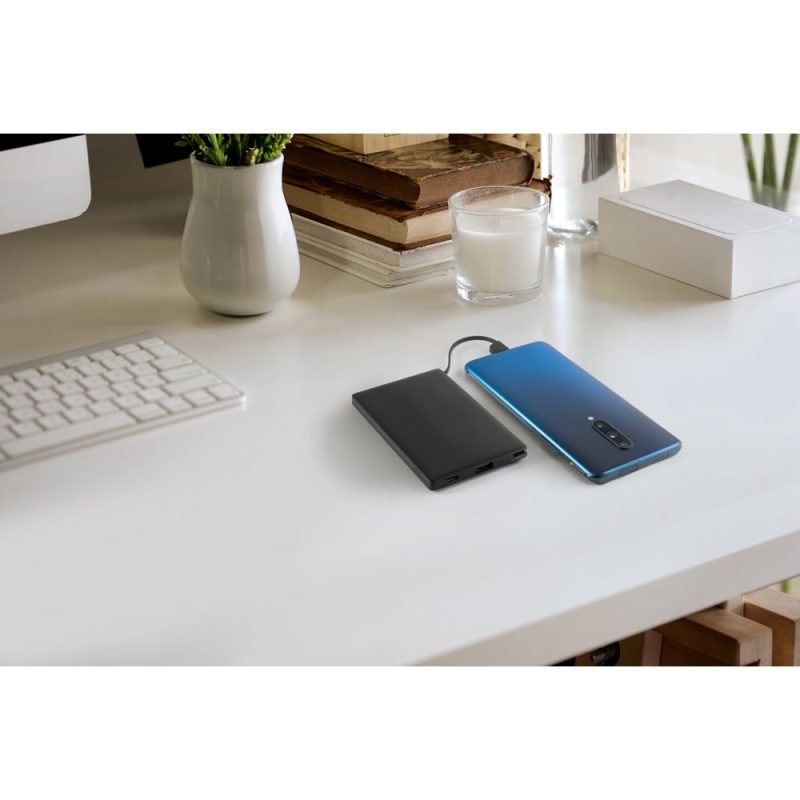 Smartphone charging with power bank on desk.