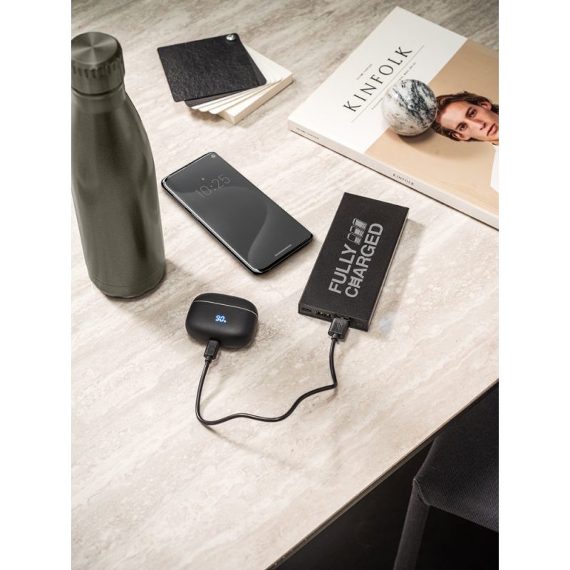 Phone and earbuds charging on marble table.