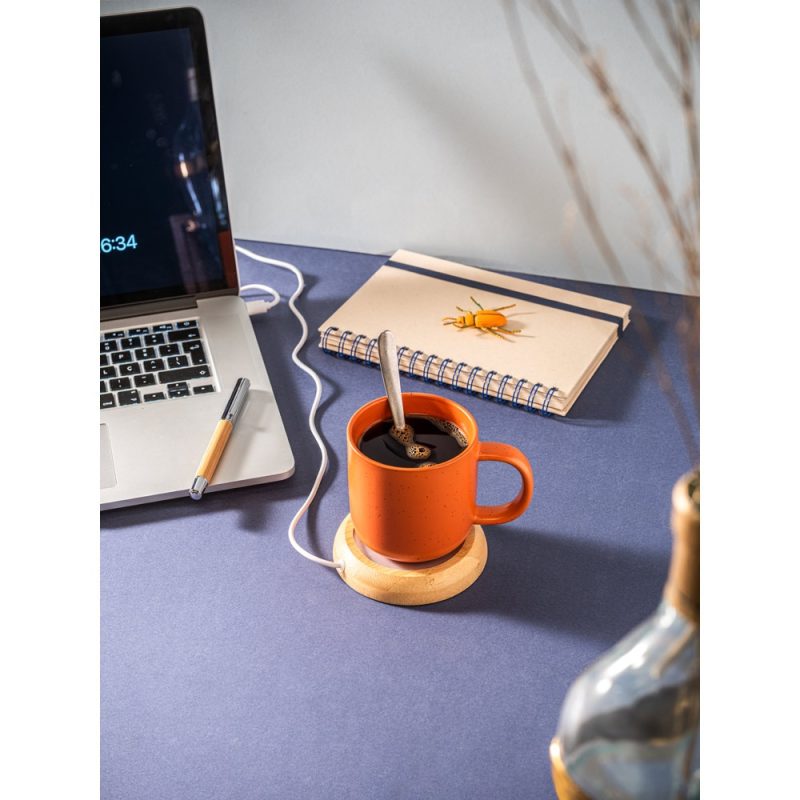 Laptop, notebook, and coffee mug on desk.
