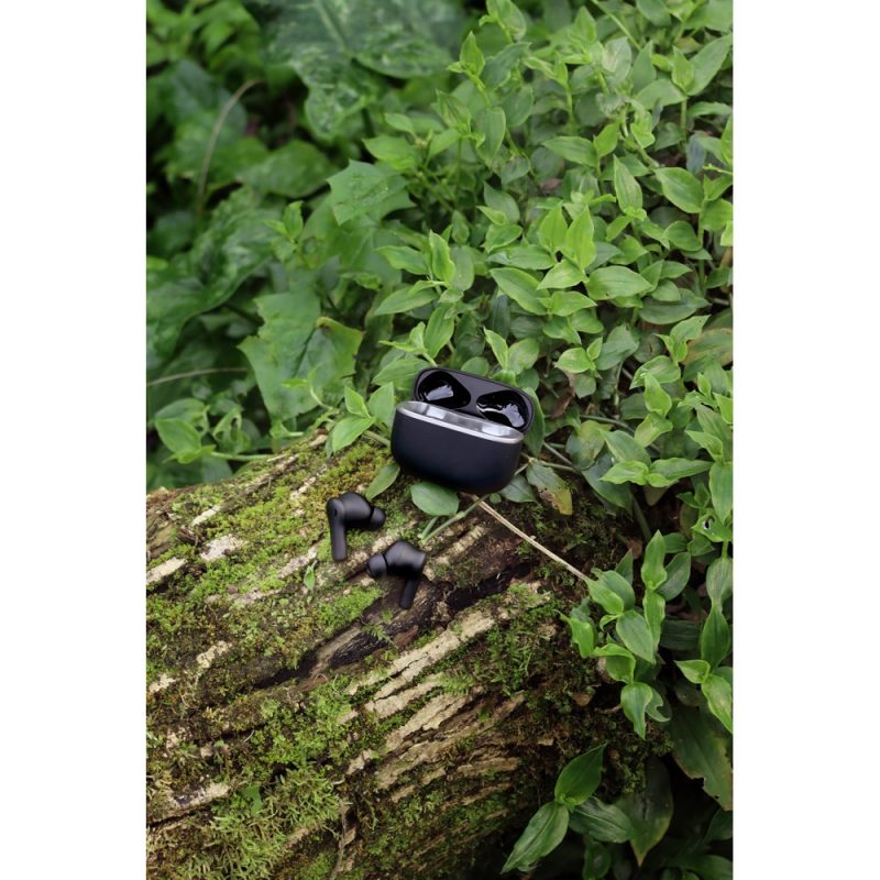 Black earbuds on mossy log in greenery