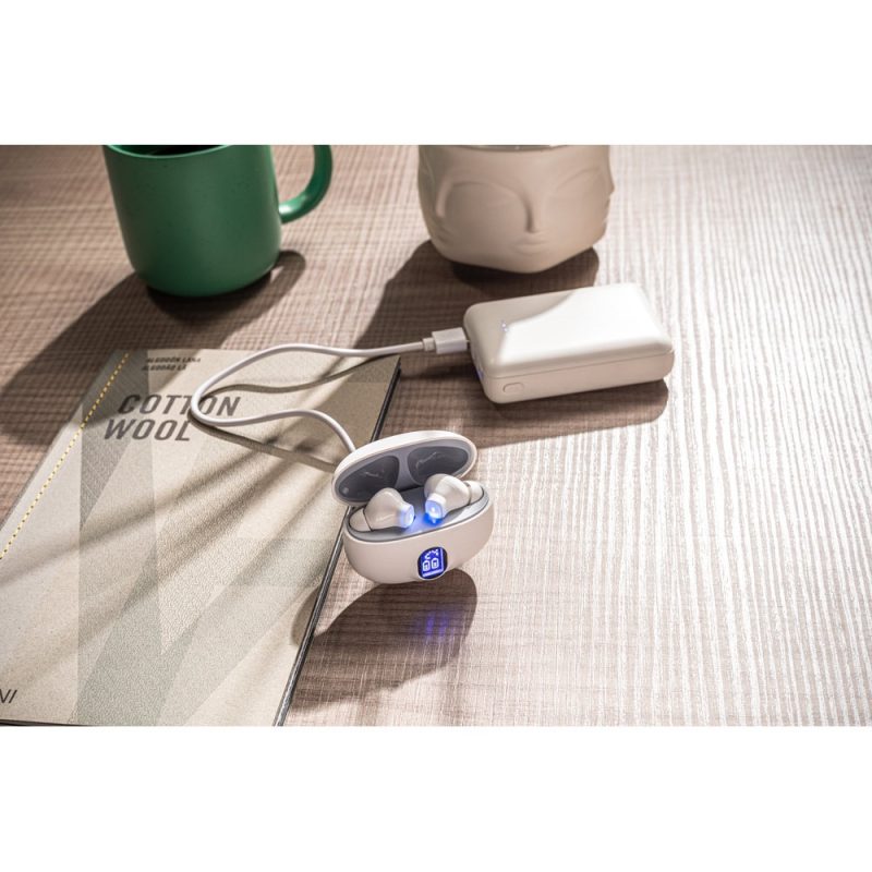 Wireless earphones charging on wooden table.