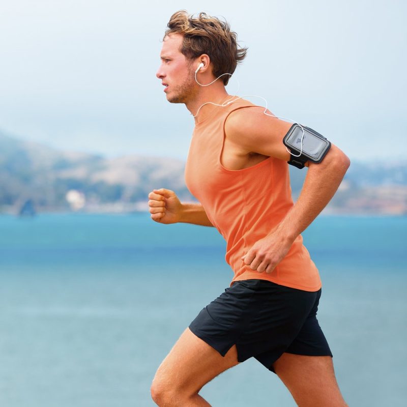 Man jogging by the sea with headphones on.