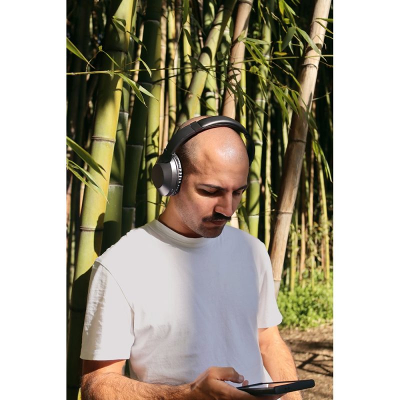 Person wearing headphones in bamboo forest.