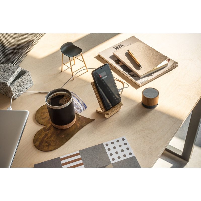 Wooden desk with coffee, phone, and speaker.