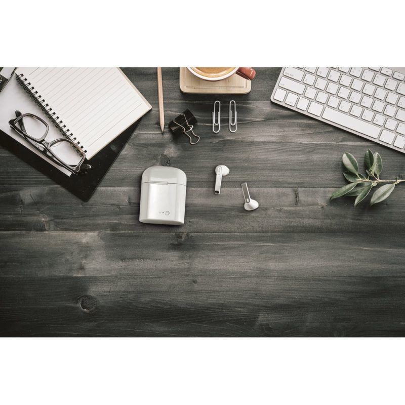 Office desk with wireless earbuds and stationery items.