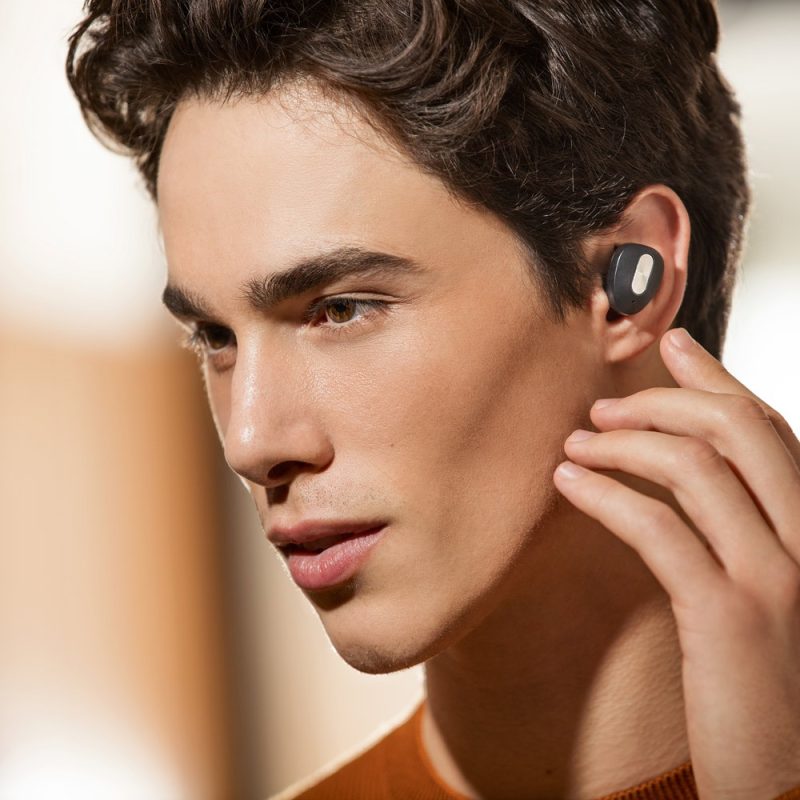 Person using wireless earbud, close-up view.
