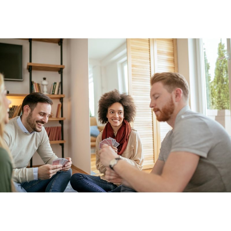 Friends enjoying playing cards indoors, smiling together.