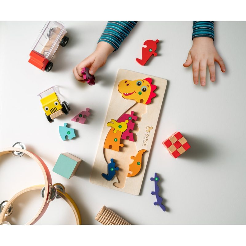 Child playing with colourful dinosaur puzzle and toys
