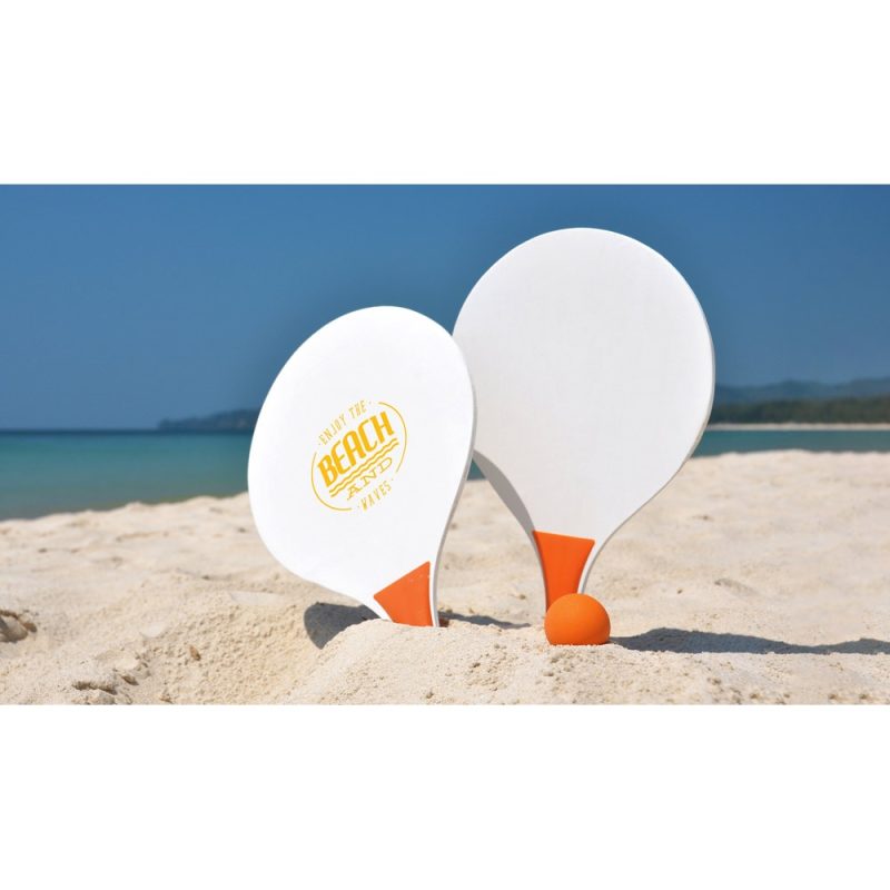Beach paddles and ball on sandy shore.